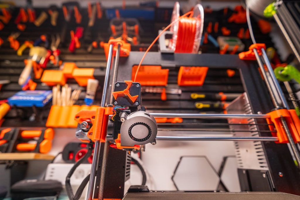 Detailed view of a 3D printer with filament and tools in a workshop setting.